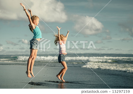 Happy girls jumping at the beach at the dawn time 13297159