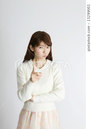 A young woman pointing at a swelling face 13299001