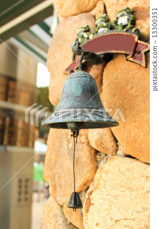 Antique bell hanging on stone wall 13300351