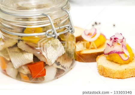pickled herring in a glass jar with potato canapes pickled herring in a glass jar with potato canapes 13303340