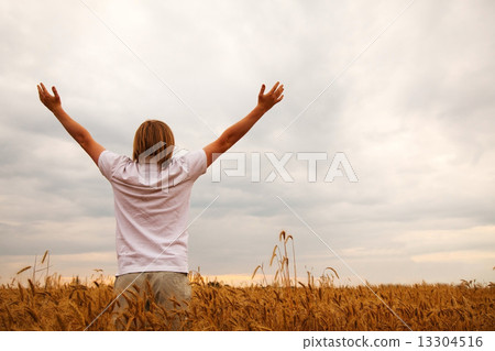 Young man staying with raised hands at sunset time 13304516