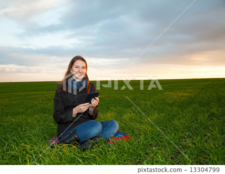 Teen girl reading electronic book outdoors 13304799