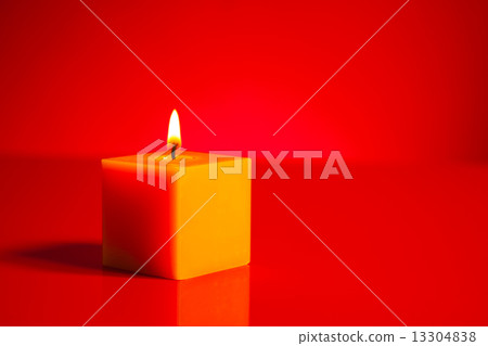 Burning yellow candle over red background Burning yellow candle over red background 13304838