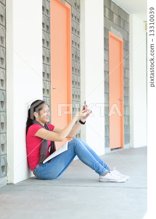 One young pan asian female student taking selfies while studying along campus corridor 13310039