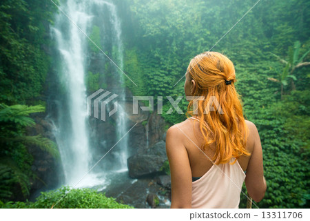 Female adventurer looking at waterfall Female adventurer looking at waterfall 13311706