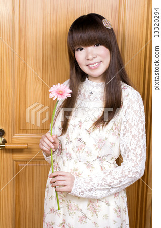 有一朵大丁草花的一名婦女在樹牆壁前面 有一朵大丁草花的一名婦女在樹牆壁前面 13320294