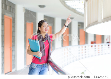 One young pan asian female student pointing a far along campus corridor One young pan asian female student pointing a far along campus corridor 13323339