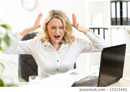 Stressed businesswoman screaming loudly at laptop in office Stressed businesswoman screaming loudly at laptop in office 13323488