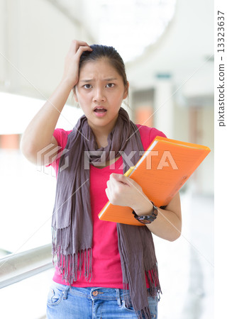 One young pan asian female student stressed over examination along campus corridor One young pan asian female student stressed over examination along campus corridor 13323637
