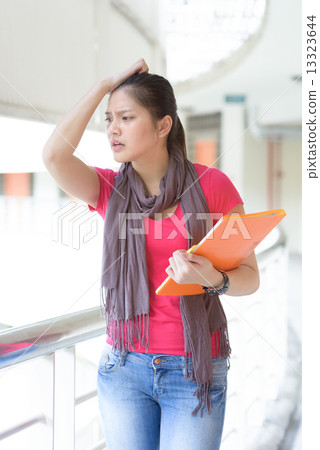 One young pan asian female student stressed over examination along campus corridor One young pan asian female student stressed over examination along campus corridor 13323644