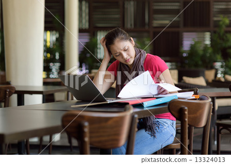 One young pan asian female student stressed over examination in campus cafe One young pan asian female student stressed over examination in campus cafe 13324013