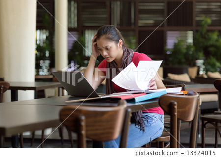 One young pan asian female student stressed over examination in campus cafe One young pan asian female student stressed over examination in campus cafe 13324015
