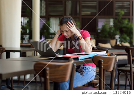 One young pan asian female student stressed over examination in campus cafe One young pan asian female student stressed over examination in campus cafe 13324016