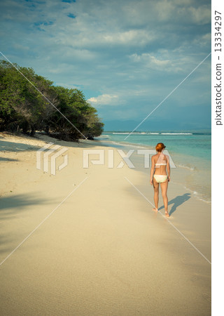 Young woman walking along tropical beach Young woman walking along tropical beach 13334297