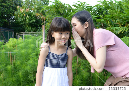 Mother and daughter sharing a secret 13335723