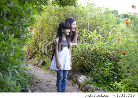 Mother and daughter in a garden 13335739