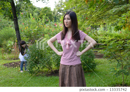 Mother and daughter playing hide and seek in a garden 13335742