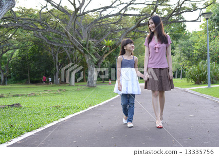 Mother and daughter walking in a park 13335756