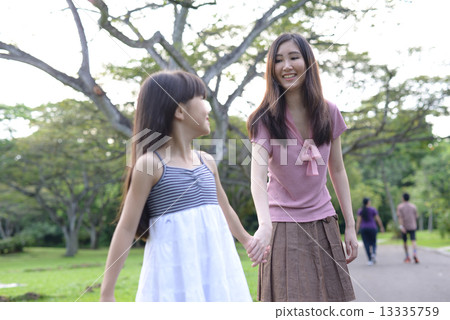 Mother and daughter walking in a park 13335759