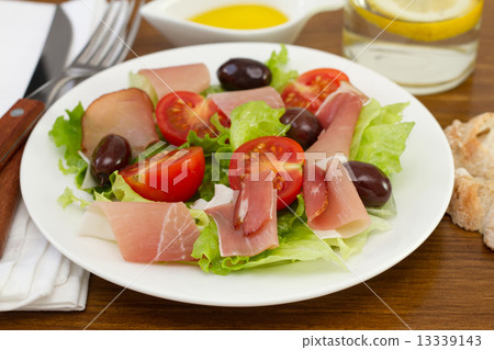 salad with prosciutto on the plate and glass of water with lemon salad with prosciutto on the plate and glass of water with lemon 13339143