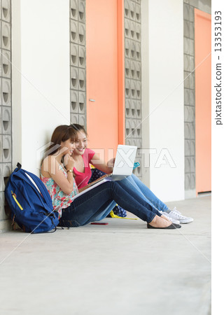 2 young female chinese student using laptop sitting along campus corridor 2 young female chinese student using laptop sitting along campus corridor 13353193