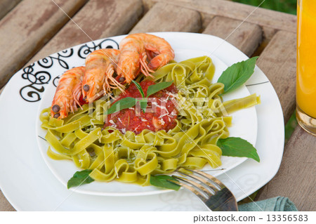A plate of spinach pasta with shrimps and tomato sauce 13356583