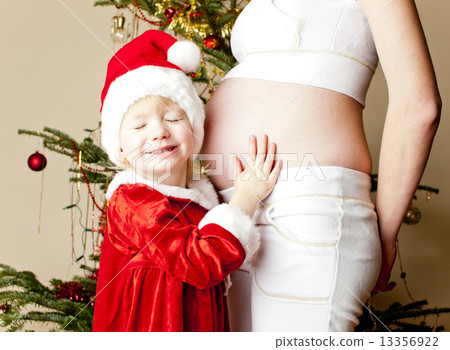 portrait of little girl and her pregnant mother by Christmas tre 13356922