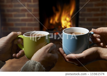 Couple With Hot Drink Relaxing By Fire Couple With Hot Drink Relaxing By Fire 13361574