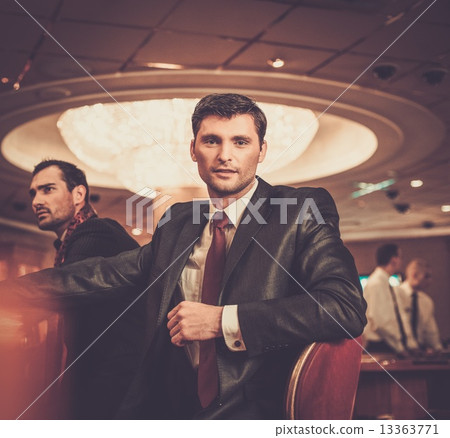 Two fashionable men in suits behind table in a casino 13363771
