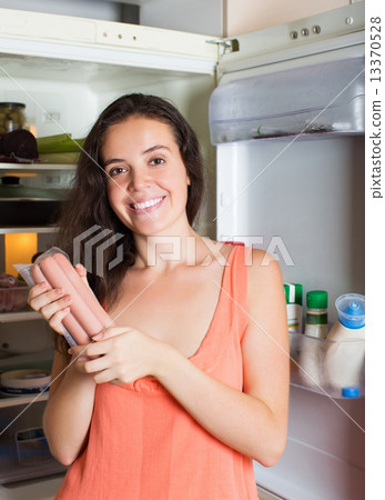 Woman taking sausages from fridge 13370528