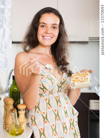 Woman eating biscuit in kitchen 13370693