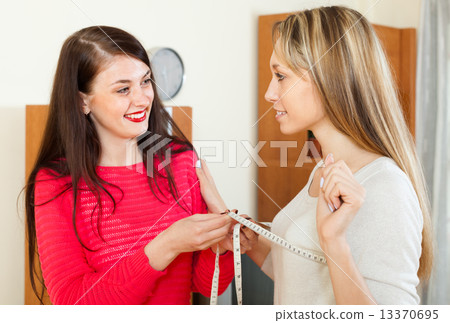 Girl measuring bust of girlfriend with measuring tape Girl measuring bust of girlfriend with measuring tape 13370695