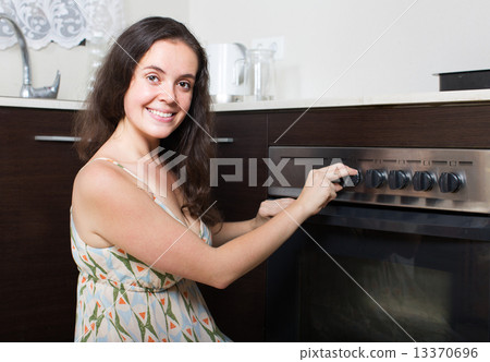 Young housewife cooking in the oven Young housewife cooking in the oven 13370696