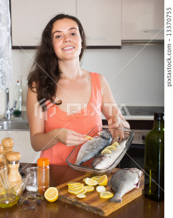 Happy housewife preparation fish in frying pan 13370755