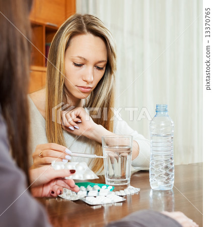 Sick person looking by thermometer, girlfriend helping her Sick person looking by thermometer, girlfriend helping her 13370765