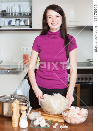Happy woman cooking rice noodles with seafood 13370906