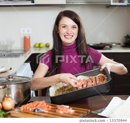 happy woman cooking fish pie with salmon 13370944