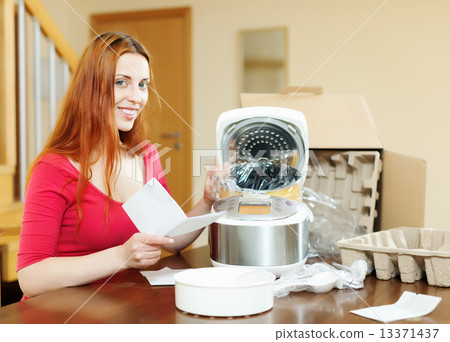 cheerful woman reading guarantee for new slo-cooker 13371437