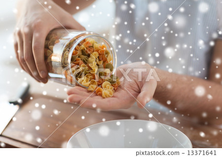 close up of man emptying jar with colorful pasta 13371641