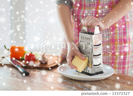 close up of woman hands with grater grating cheese close up of woman hands with grater grating cheese 13372327