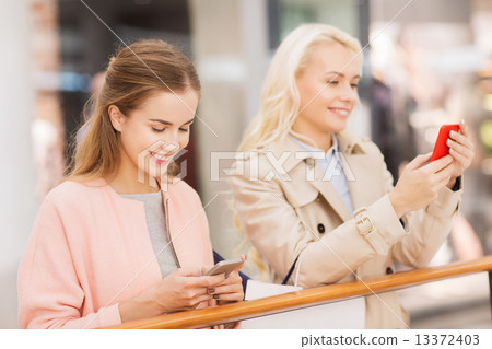 happy women with smartphones and shopping bags 13372403