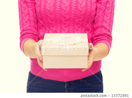 close up of woman in pink sweater holding gift box 13372891