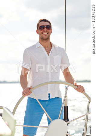 young man in sunglasses steering wheel on yacht 13373219