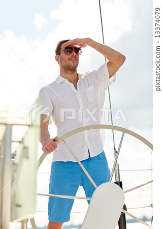 young man in sunglasses steering wheel on yacht 13374079