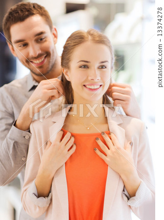 Stock Photo: couple trying golden pendant on at jewelry store