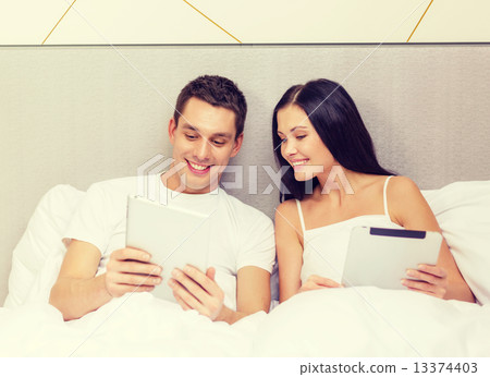 smiling couple in bed with tablet pc computers 13374403