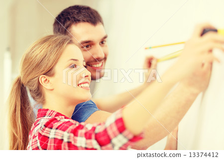 smiling couple measuring wall 13374412