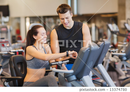 happy woman with trainer on exercise bike in gym happy woman with trainer on exercise bike in gym 13374780