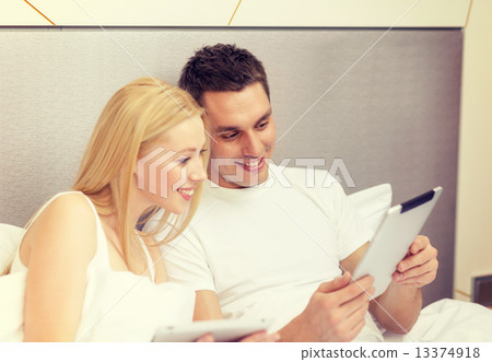 smiling couple in bed with tablet pc computers smiling couple in bed with tablet pc computers 13374918