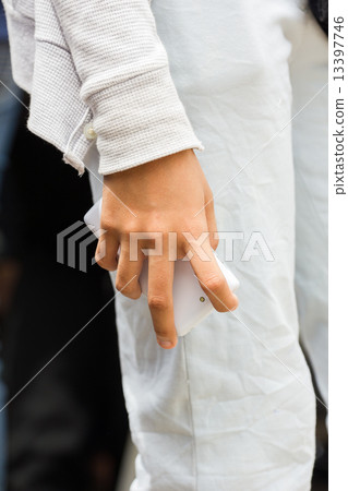 hand of woman holding white mobile phone on the side of her leg hand of woman holding white mobile phone on the side of her leg 13397746
